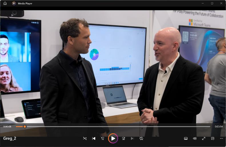 Two men in a meeting room with a laptop and video conferencing equipment